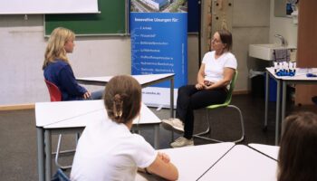 Pictured are Bettina Liegl and a student from Anton Bruckner Grammar School. They are sitting across from each other at a table, practicing a job interview.