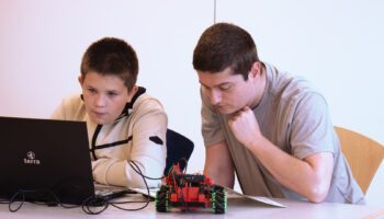 The trainer of the IT and Software department helps a child.