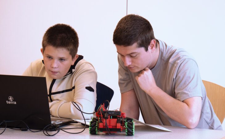 The trainer of the IT and Software department helps a child.
