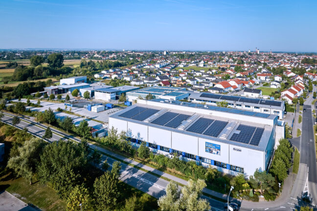 Auf dem Foto sieht man die Firmengebäude Werk 1 und Werk 2 von insgesamt drei Werken. Auf den Dächern der Werke sind flächendeckend PV-Anlagen montiert.