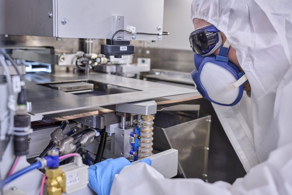 Person in Schutzausrüstung steht vor der Laserstation und schaut diese an